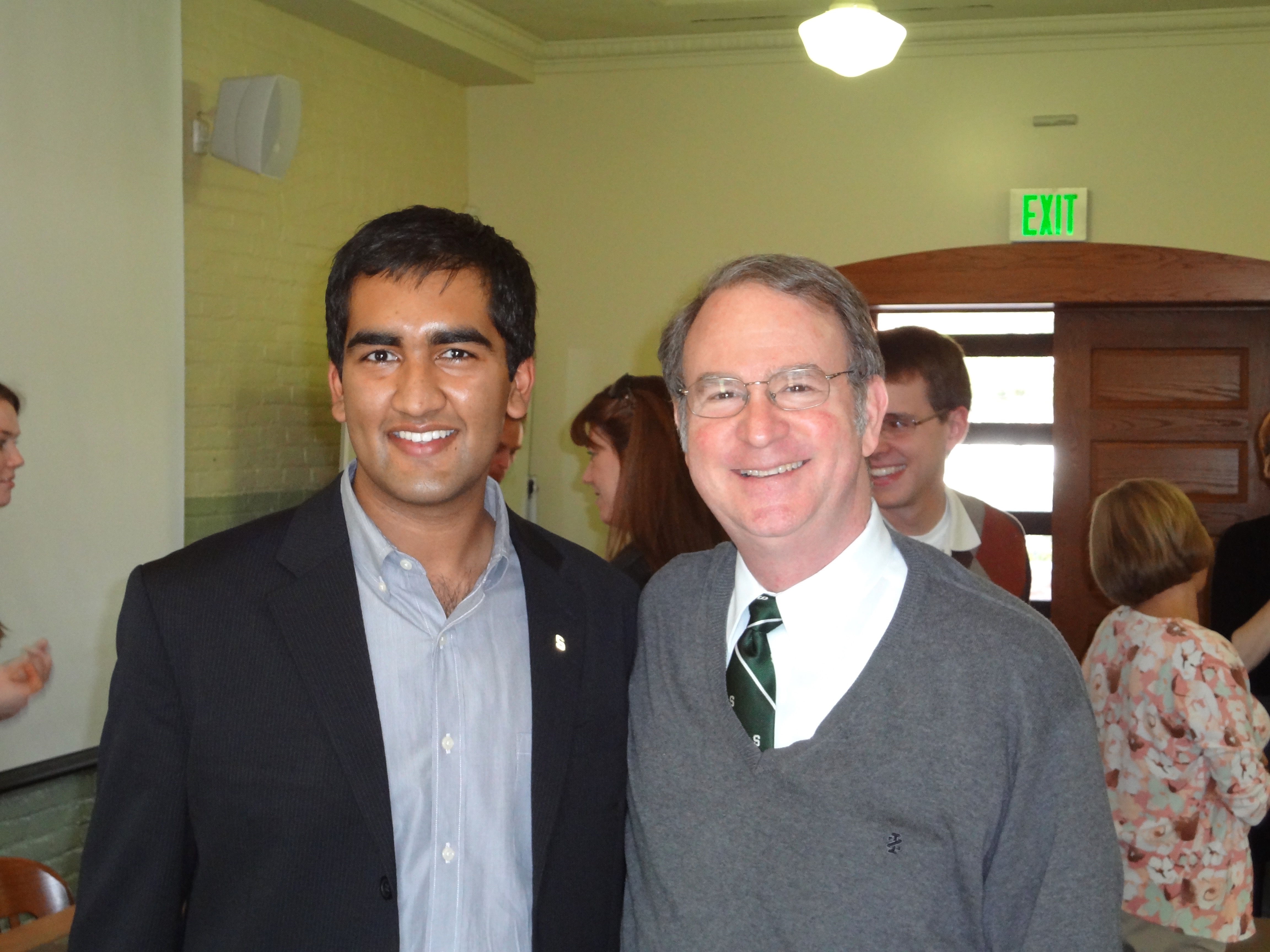Two men standing and smiling for a photo in a classroom.