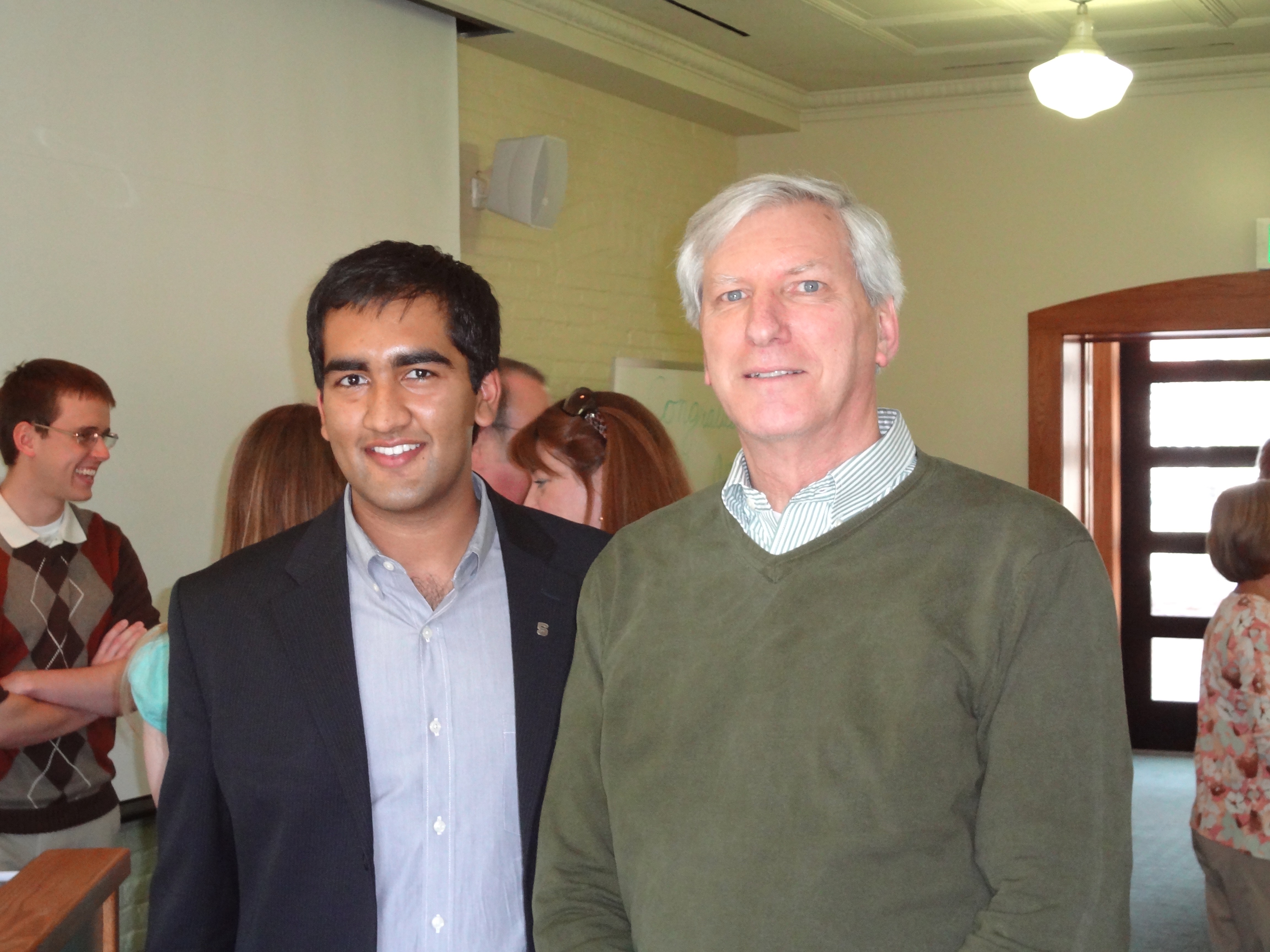 Two men standing and smiling for a photo in a classroom.
