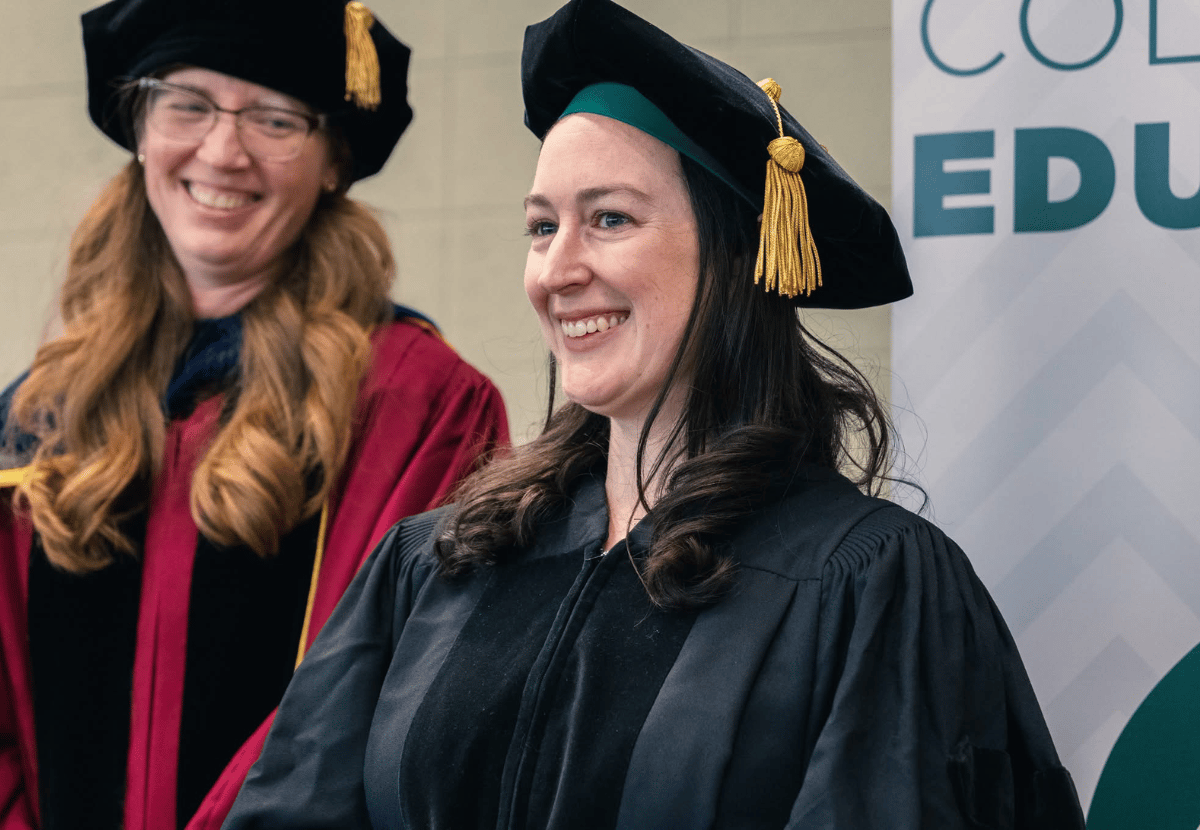 Doctoral Degree Candidate wearing regalia and smiling