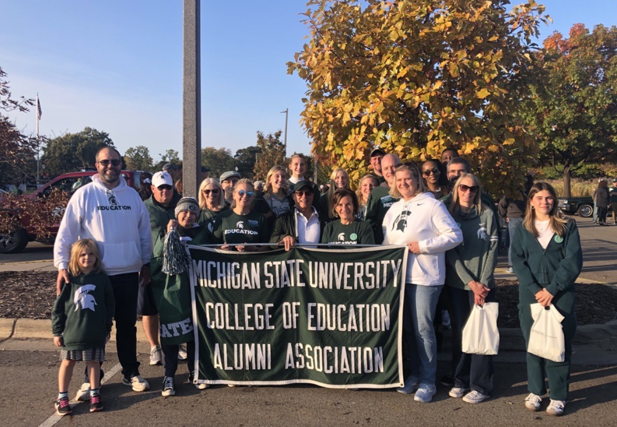 Group of CED Alumni Board and volunteers holding a banner that reads "Michigan State University College of Education Alumni Association"