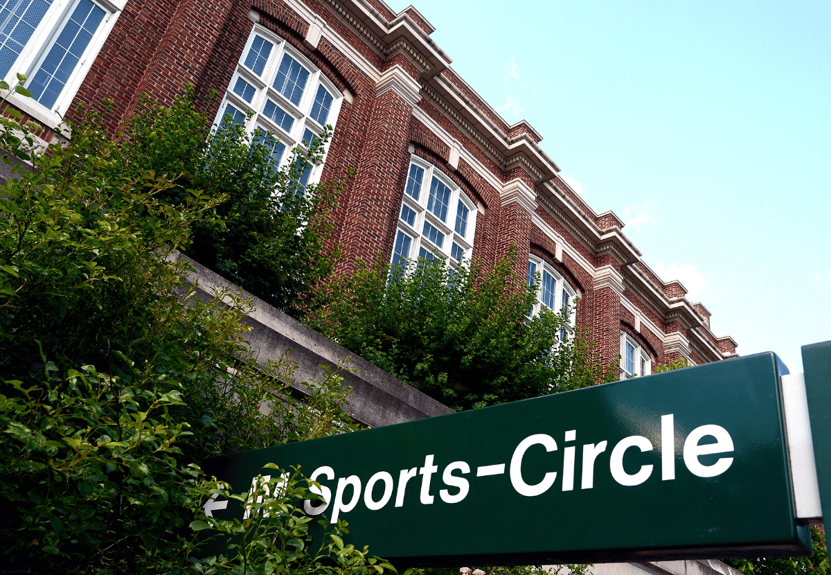 IM Circle sign outside of the IM Circle building. Building is a two-story brick structure with green bushes in front.