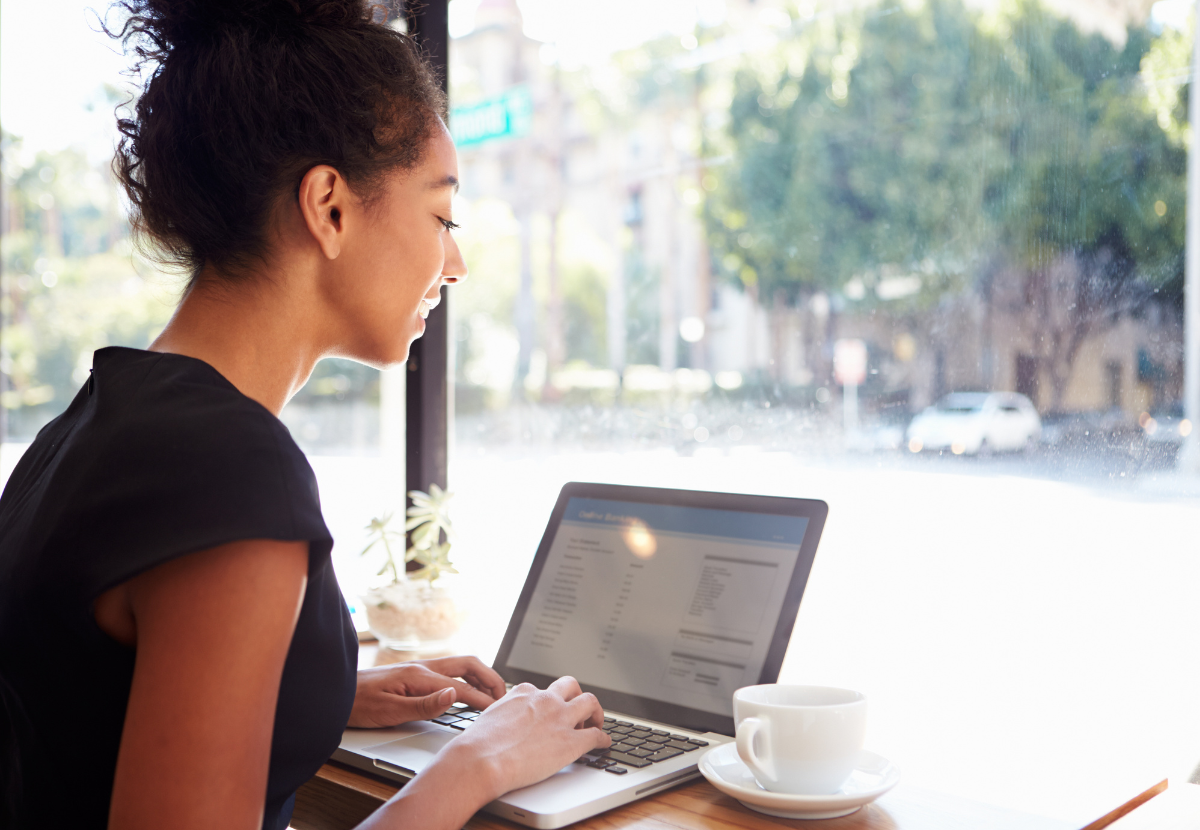 Woman working on a laptop in front of a window.