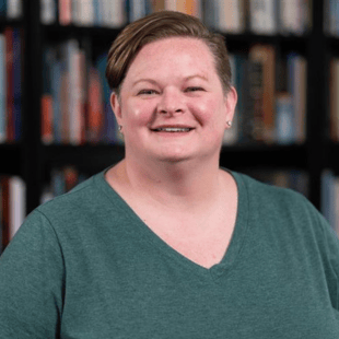 Brittany Dillman wearing a green shirt. There are bookshelves out of focus in the background.