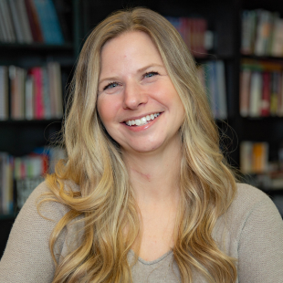Headshot of Lisa Dunlap wearing a light brown shirt. She has blonde hair. Lisa is standing in front of a bookshelf.