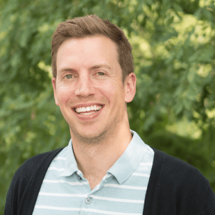 Michael Haslett wearing a light blue stripe polo with a dark blue jacket. 