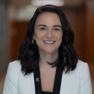 Samantha Lam weaing a black and white jacket with a green Spartan lapel pin.