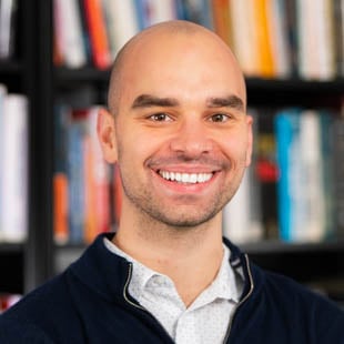 Headshot of Eric Leszczynski wearing a dark jacket and white shirt.
