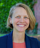 Alyssa Morley headshot. Alyssa stands in front of green foliage and smiles for the camera.