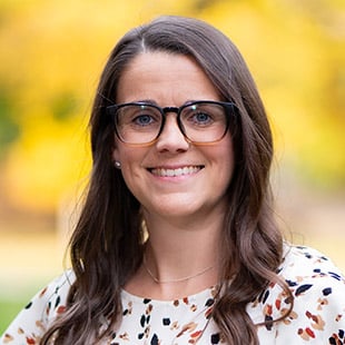 Headshot of Katrina Smith wearing a white blouse and glasses