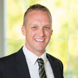 Headshot of Chad Wiggins wearing a dark suit jacket, striped tie and white shirt