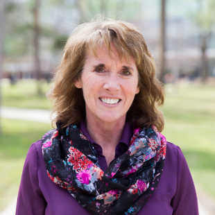 Headshot of Heather Williamson wearing a purple shirt with a dark floral scarf.