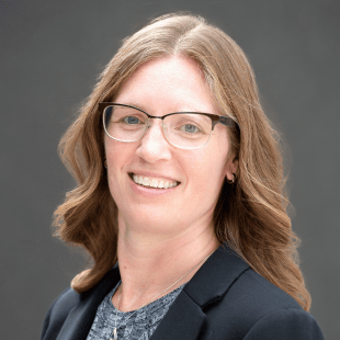 Sara Witmer wearing a dark jacket and glasses.
