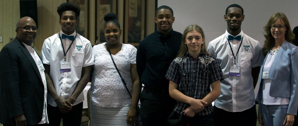 Group stands smiling and posing for the camera