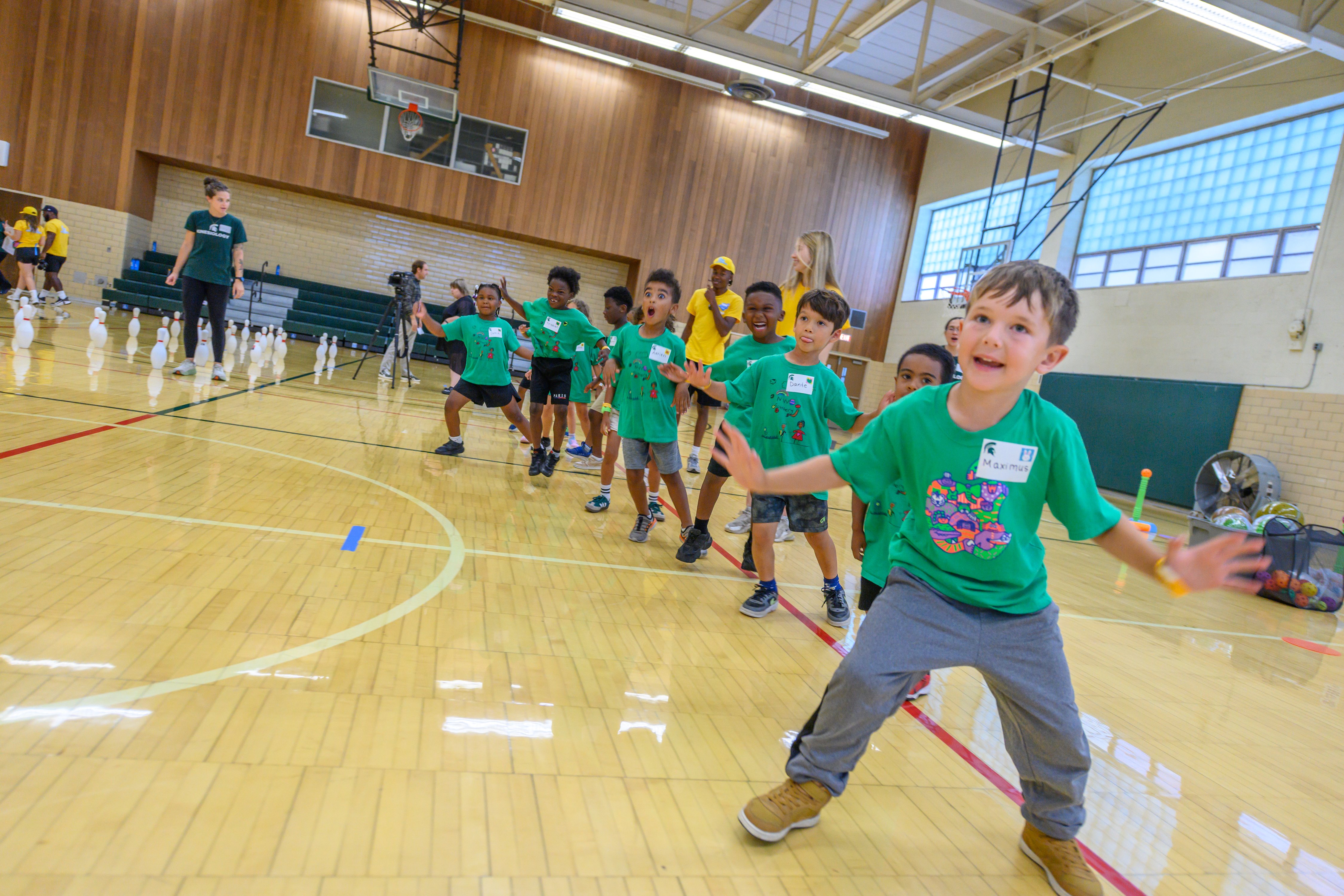 Young children line up for an activity in IM Sports circle. The children wear bright green shirts.
