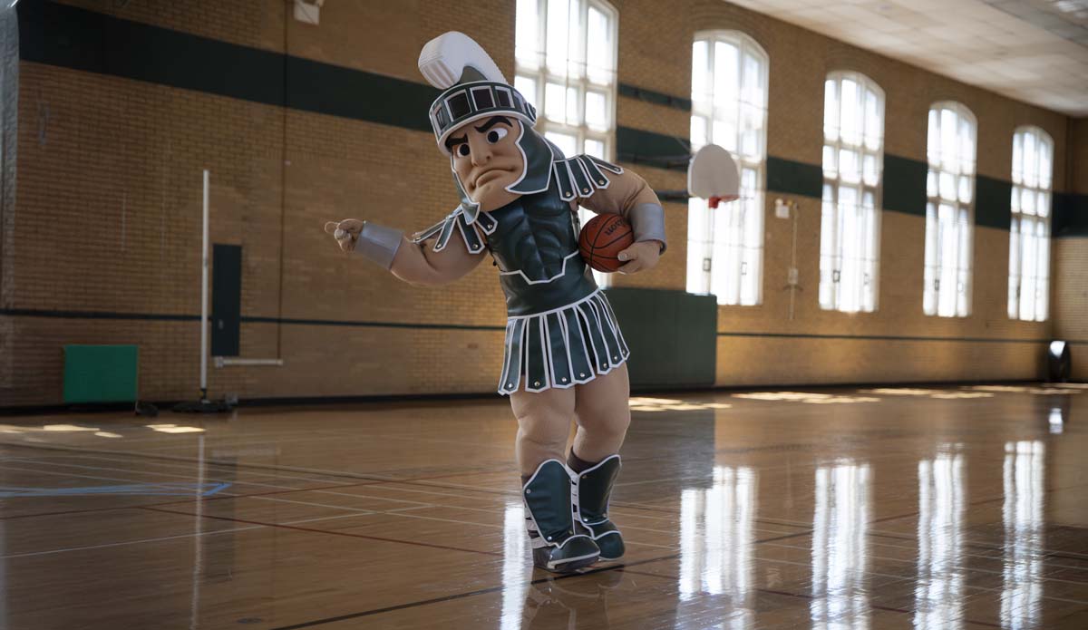 Sparty, MSU's mascot, stands in a gymnasium in IM Sports Circle and points to something off-camera.