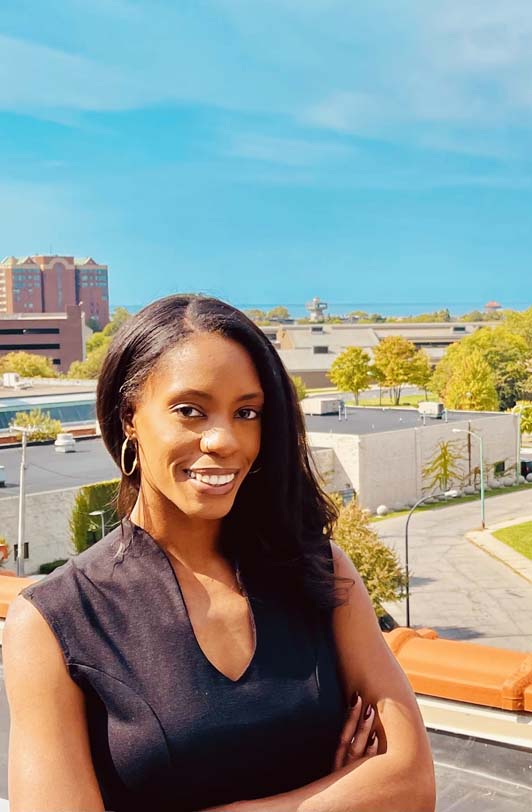 Brittany Jones poses for the camera in front of a cityscape.
