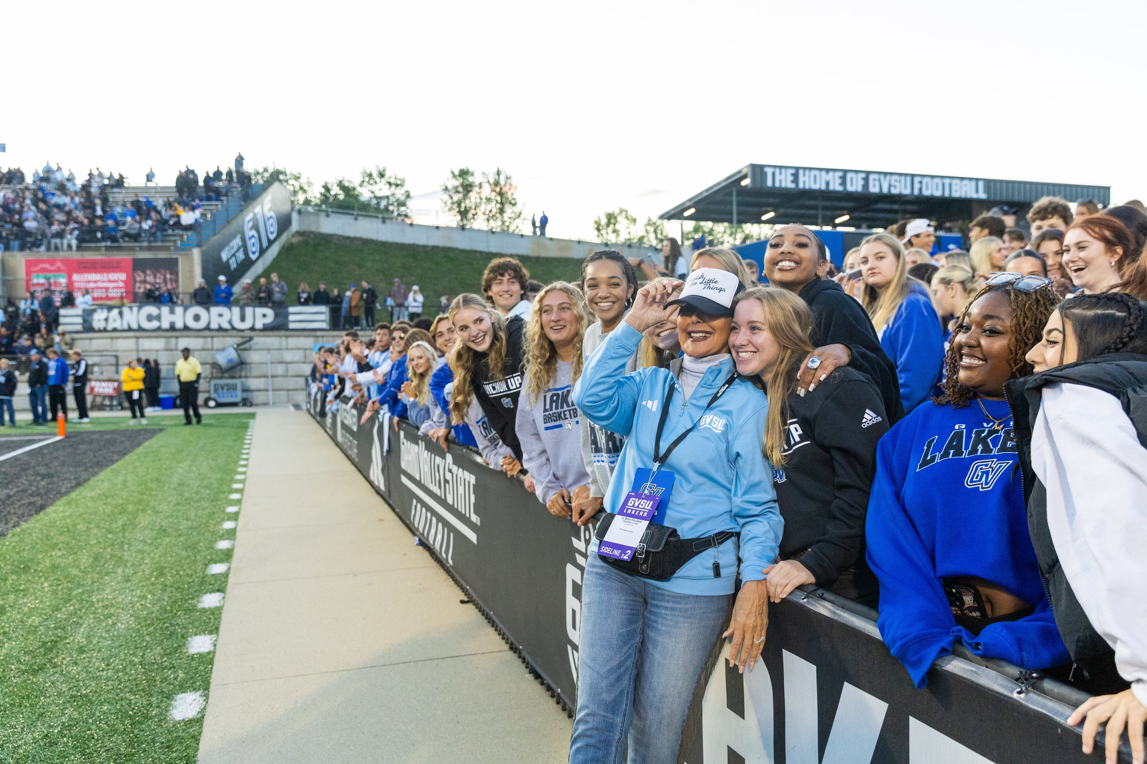 A group of Grand Valley State University students and supporters smile for a photo at a football game. 