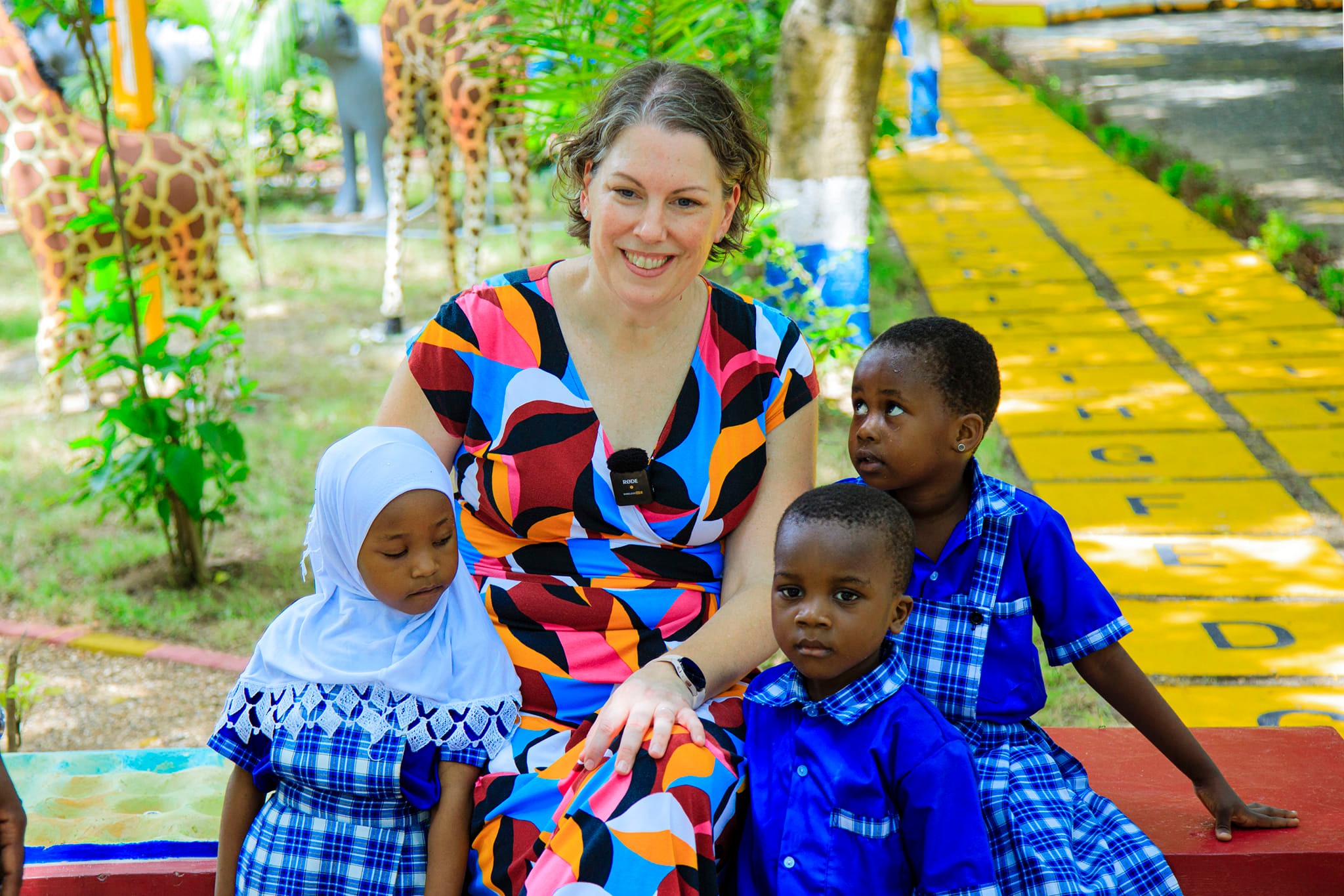MSU scholar Bethany Wilinski is seated on a bench on a playground with children in Tanzania. 
