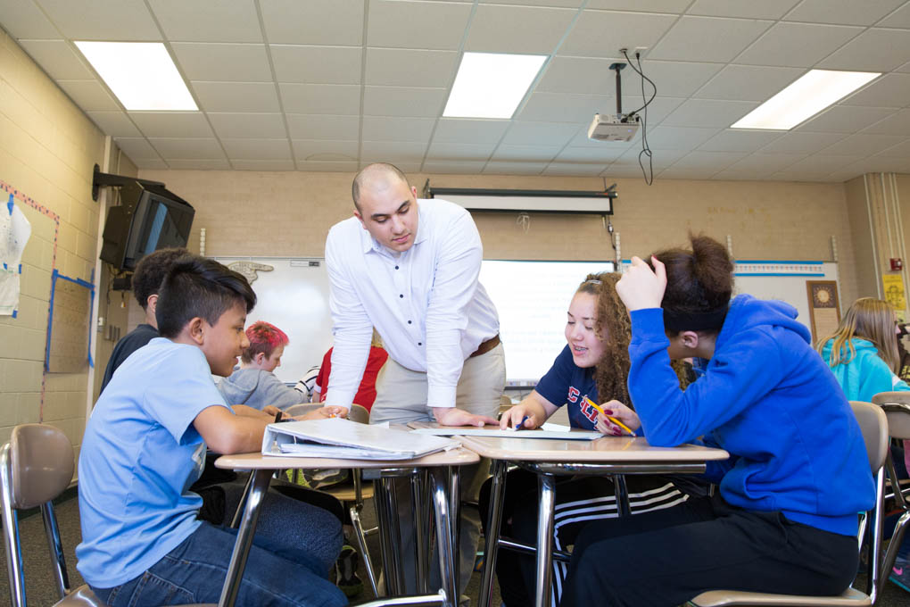 teacher observing students collaborating on a project