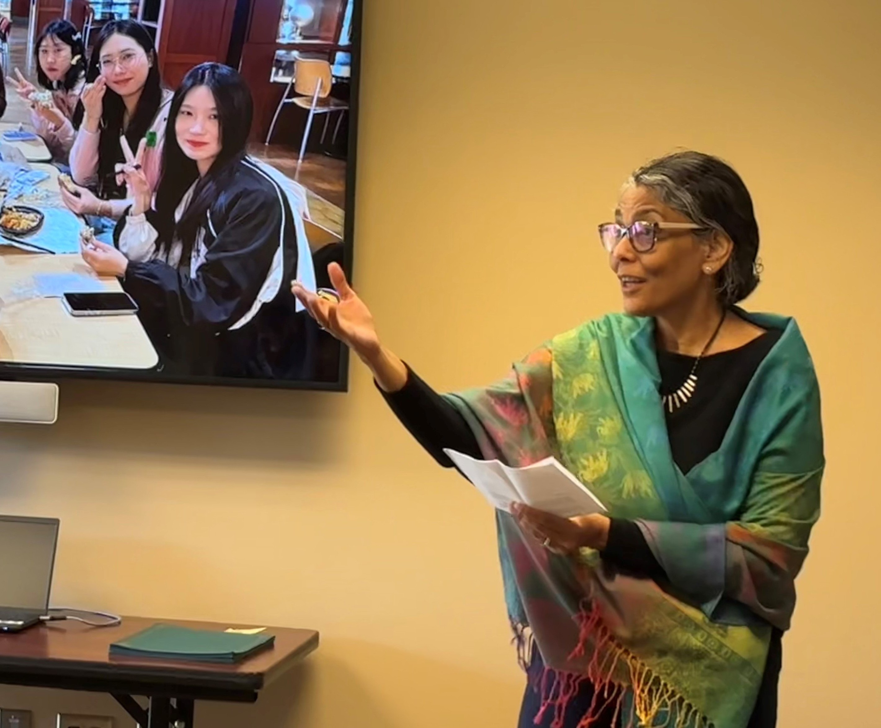 amita presenting while a slideshow of students is in the background