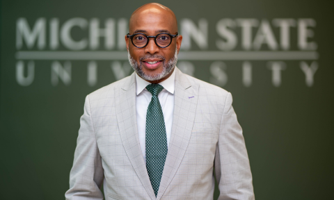 Dean Jerlando Jackson stands in front of a sign that reads Michigan State University.