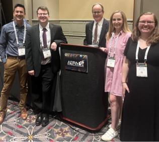 AERA event with people posing by a speakers podium
