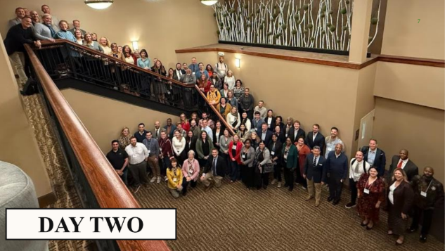 attendees in a large conference room with a staircase