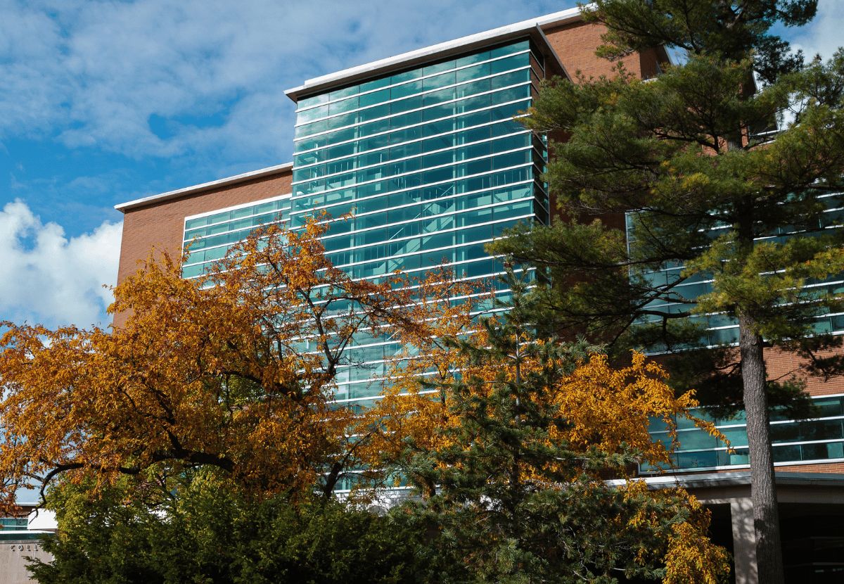 Front of Erickson Hall glass stairwell with fall trees in the foreground