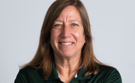 Sally Nogle headshot. Nogle wears an MSU green polo. Nogle's dark blonde hair is about shoulder-length. Nogle is situated against a light gray neutral background.