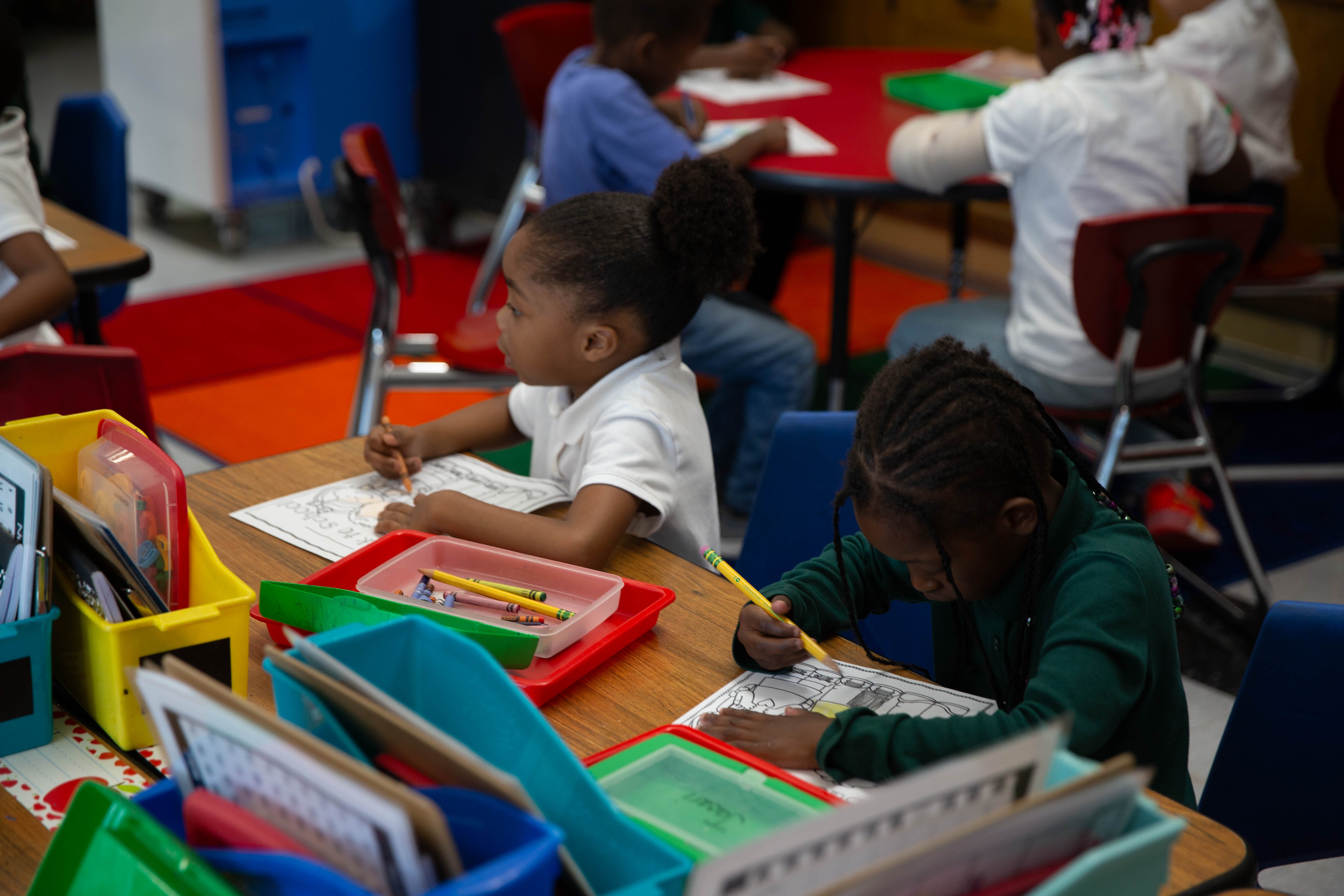 children in a classroom coloring at their desks