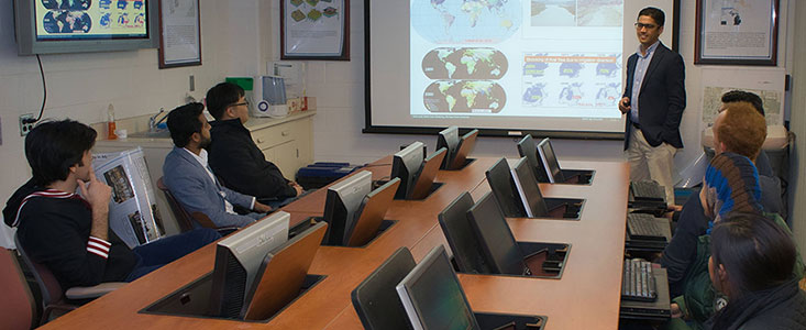 Meeting room where someone is presenting to a group of people that are sitting at a table