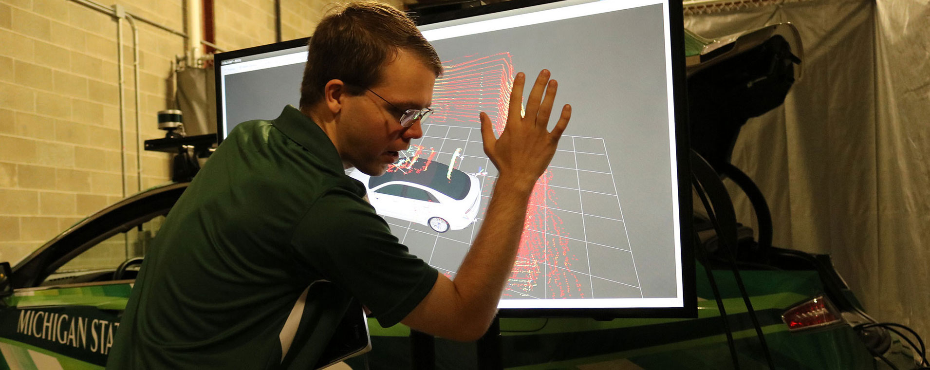 Grad Student on the computer, looking at a 3d model of a car