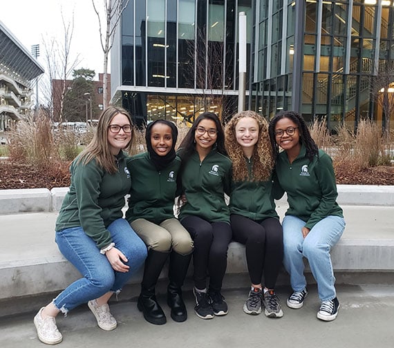 Women in engineering group sitting outside the STEM building