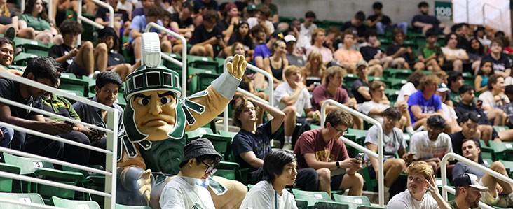 Sparty sitting in the crowd of students