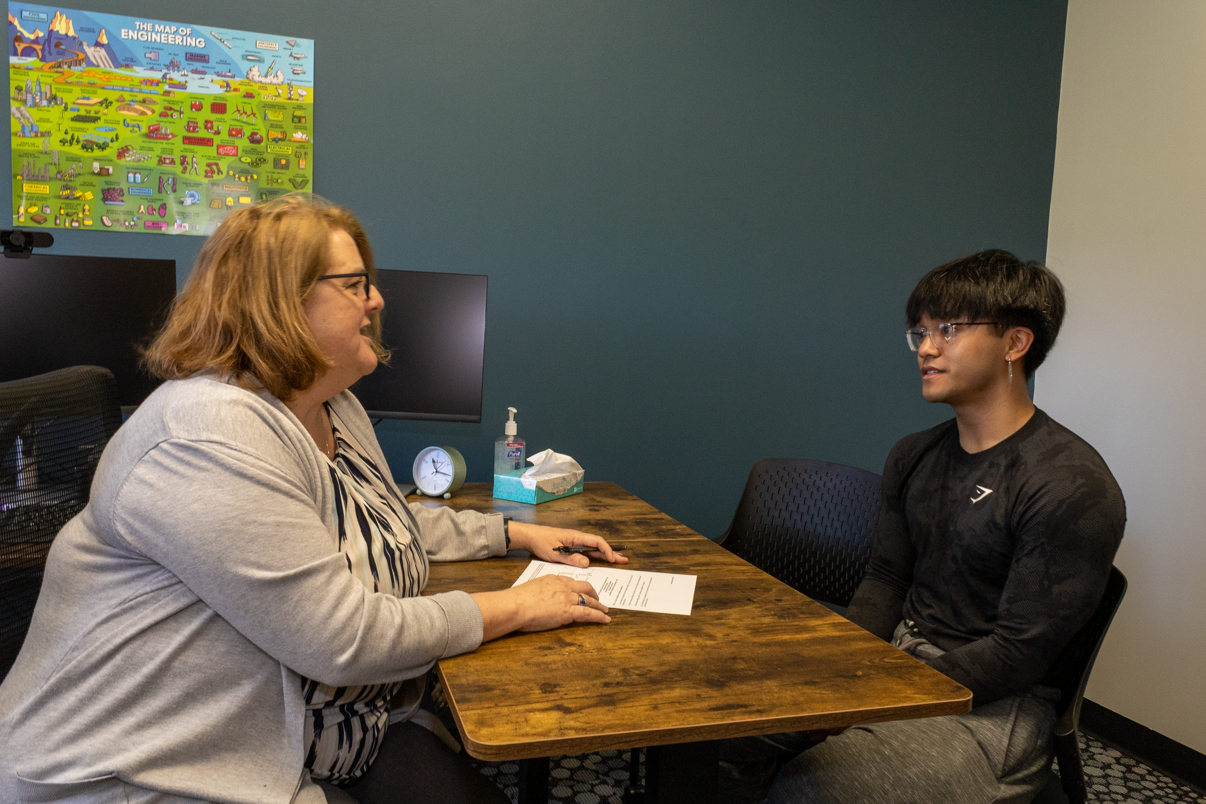 An advisor and a student meet at an office table.