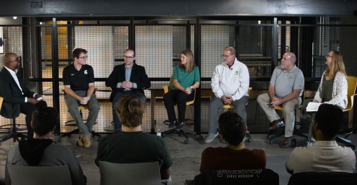 seven people sitting in chairs talking