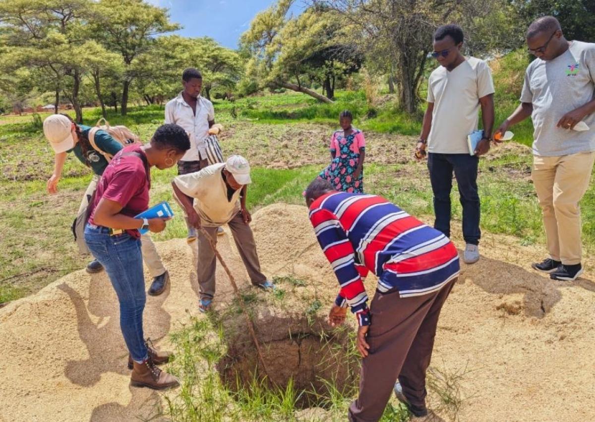 Group of people looking into a well