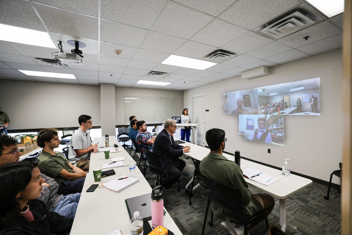 A classroom full of people watching screens at the from top the room.