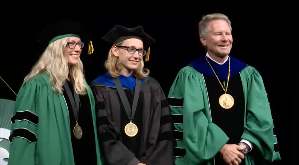 Three people standing in colorful green and black academic regalia - Provost Laura Lee McIntyre, Red Cedar Distinguished Professor Kristen Cetin, and MSU President Kevin Guskiewicz