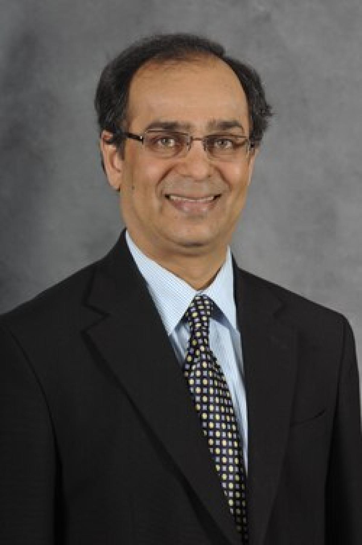 Portrait photo of Venkatesh Kodur, a man in glasses wearing a suit, tie and white shirt.