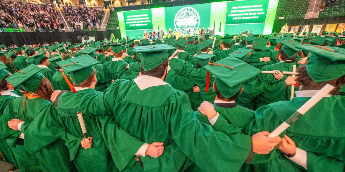Spartan Engineers stand in green academic regalia and mortar boards at graduation.