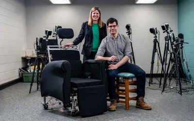 Two people pose next to a chair for the Sit Sense innovation that reduces pressure sores