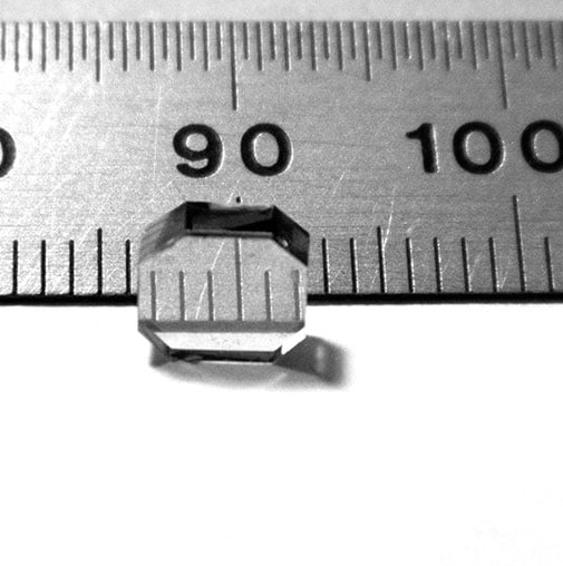 close up of a diamond crystal next to a metal ruler