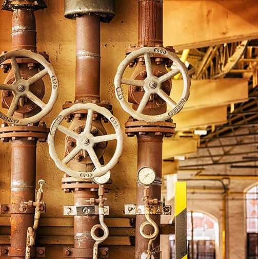 close up of industrial pipes with adjustment wheels