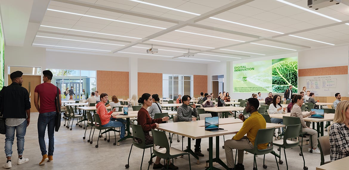 Modern classroom with students seated at tables using laptops, large screen displays “Digital Innovation.”