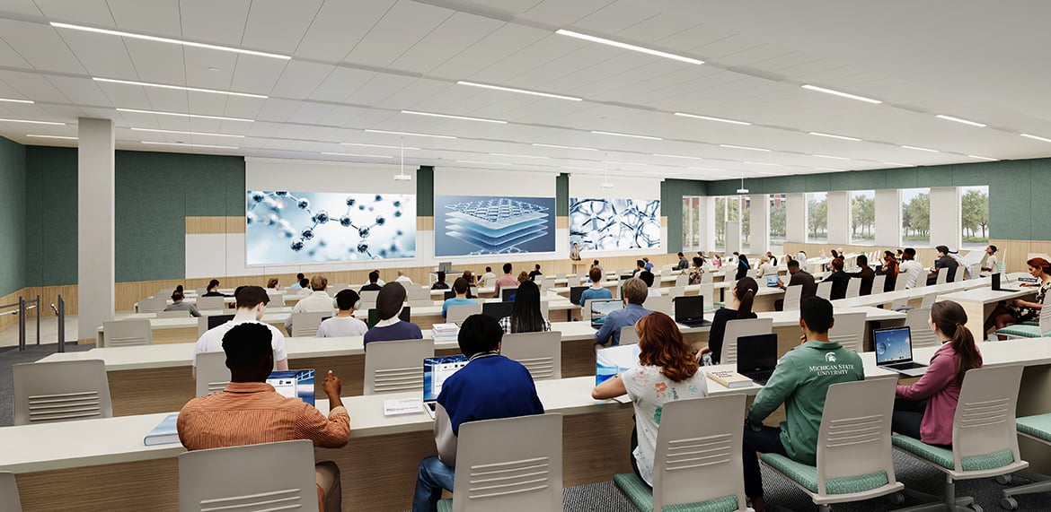 Large lecture hall with tiered seating, students using laptops, and scientific graphics on big screens.