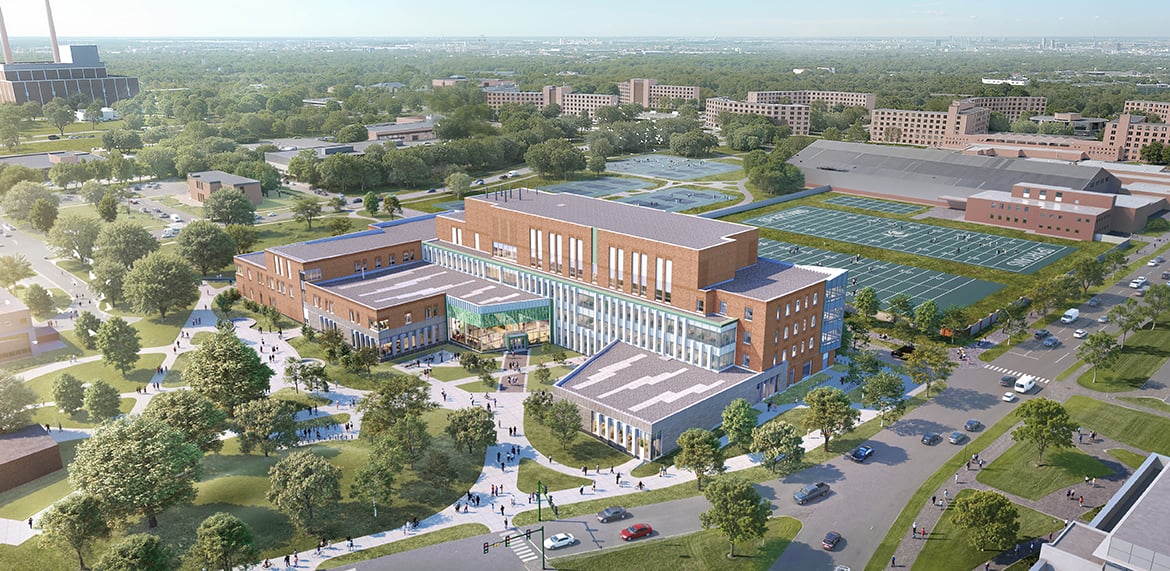 Aerial view of a large campus building with sports fields and surrounding greenery.