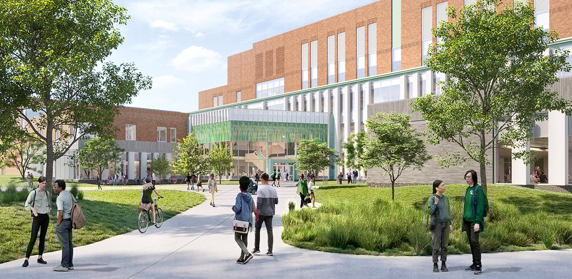 Exterior view of a modern academic building with glass entrance, landscaped courtyard, and people walking.