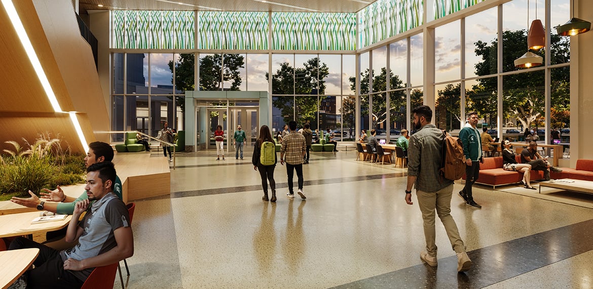 Spacious lobby with tall windows, modern seating, and people entering and chatting.