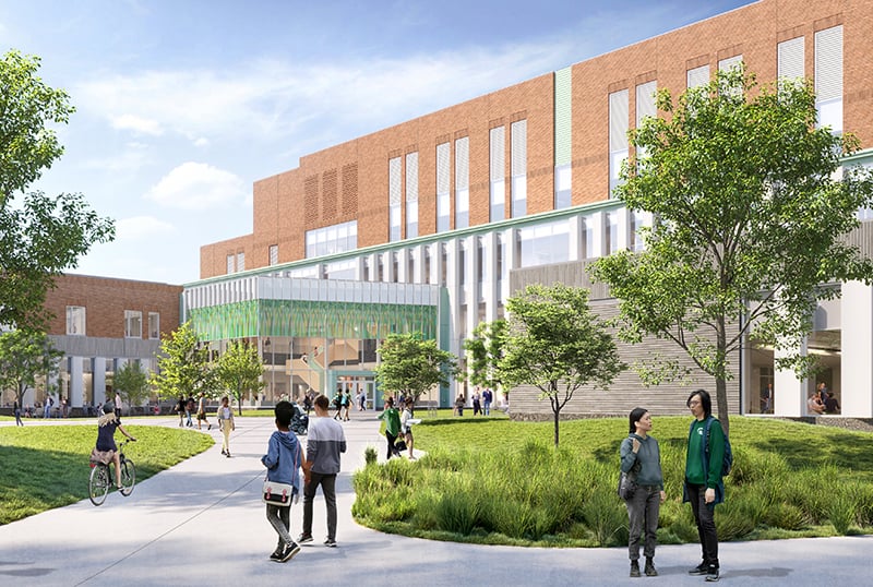 Exterior view of a modern academic building with glass entrance, landscaped courtyard, and people walking.